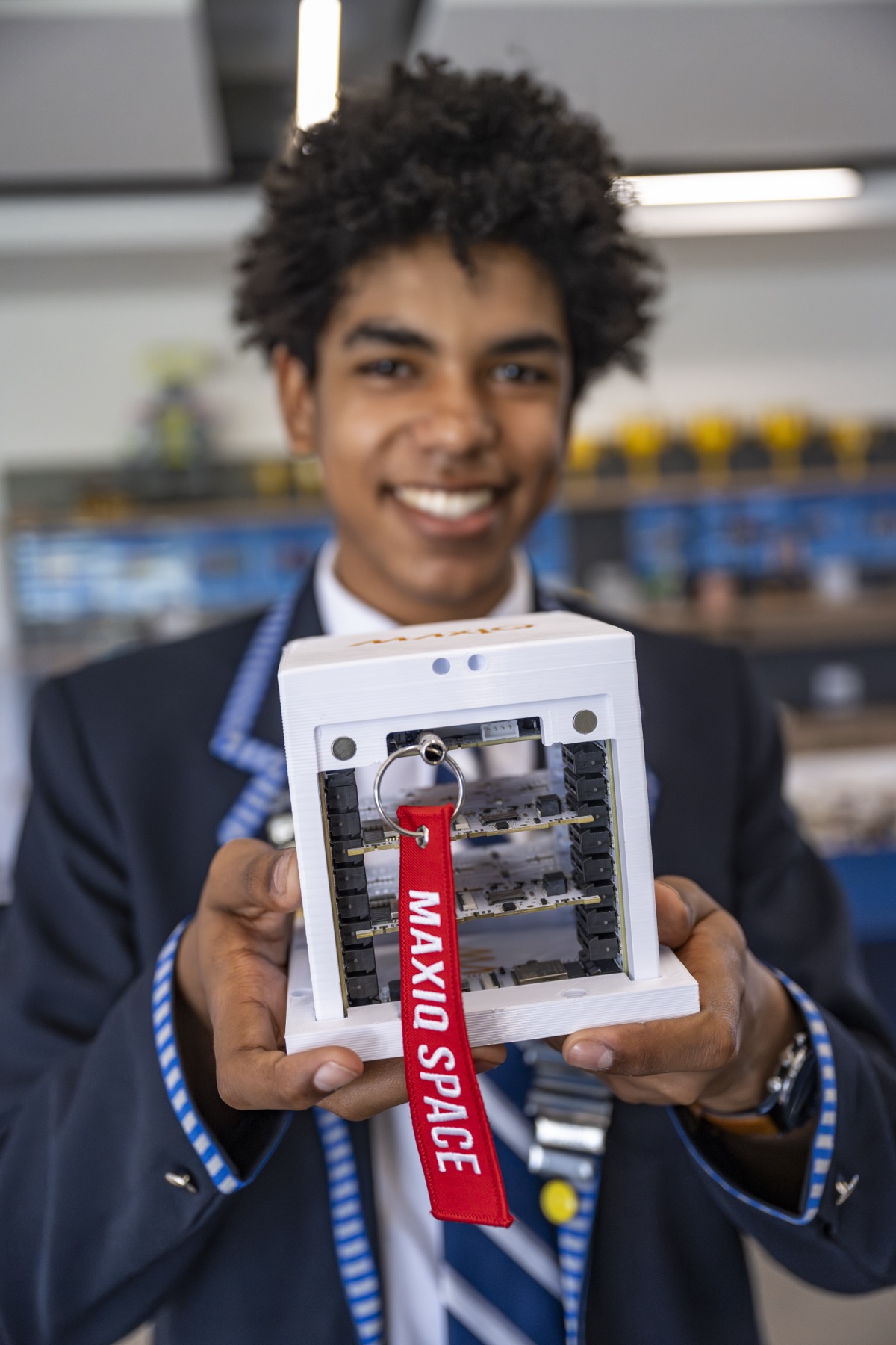 A student holding a 3D-printed MaxIQ satellite housing