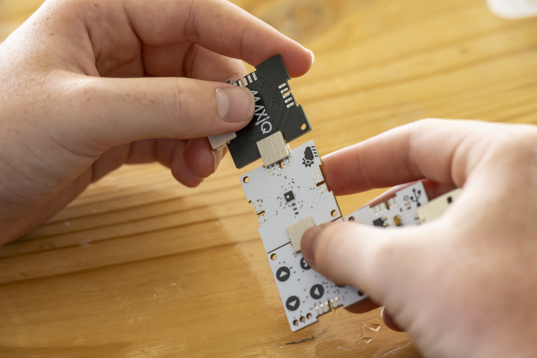 Close-up of hands assembling a MaxIQ circuit board